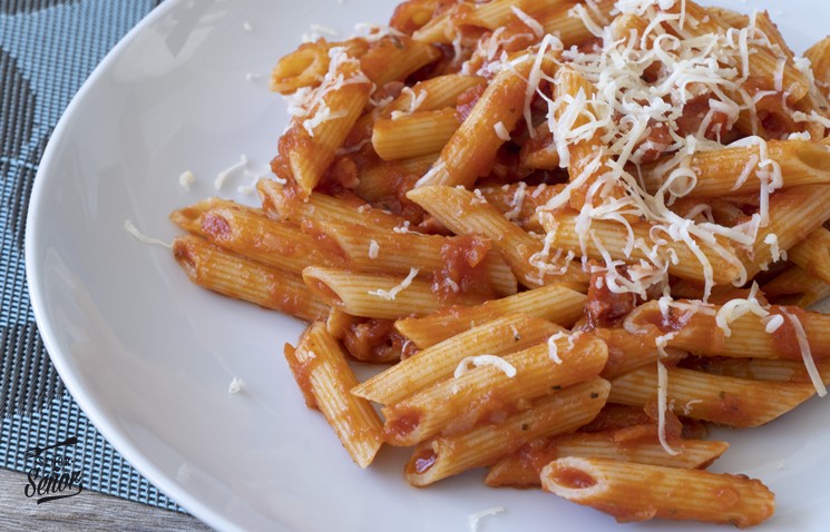 Un plato de macarrones con tomate y queso