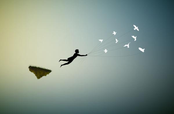 Una persona volando en el cielo enganchado a unos pájaros blancos con una cuerda