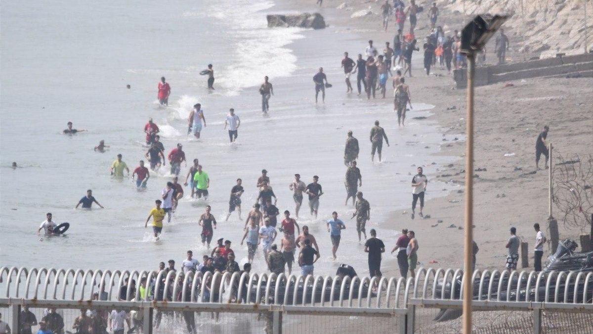 Personas migrantes tratando de entrar al país desde la playa.