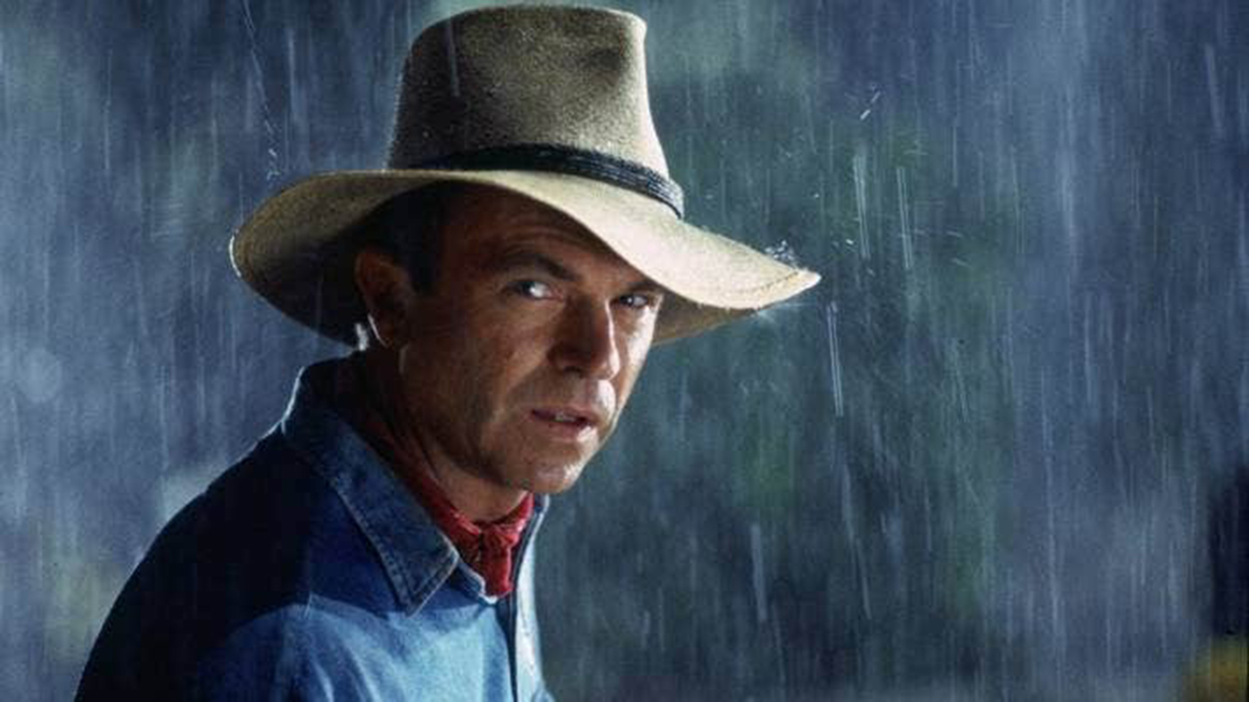 Sam Neill mirando a cámara con sombrero de vaquero mientras llueve de fondo