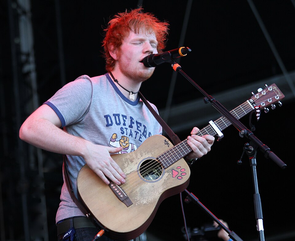 Ed Sheeran cantando y tocando la guitarra en un concierto